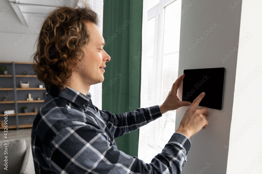 Aufkleber Man Using Smart Home Application Via Tablet On Wall Indoor