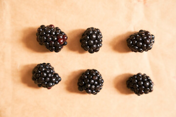 Six blackberries on a beige craft paper background. Berries laid out in the form of a rectangle. Horizontal card. Healthy, delicious, natural vegetarian background.