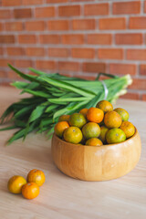 Fresh orange in the wooden bowl put on the wooden table with the pandanus behind. Orange is a healthy fruit and have refreshing sweet taste.
