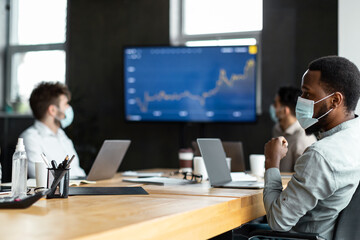 Colleagues having meeting in boardroom, sitting at desk
