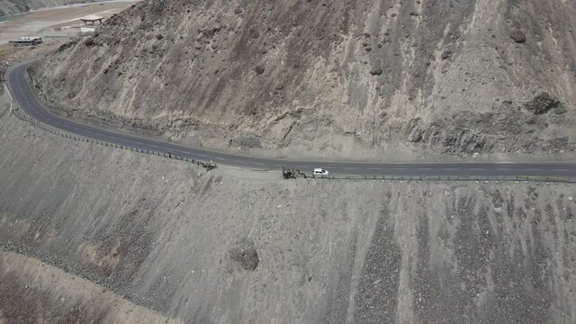 Aerial view of an army truck passing on high road in the mountains. Drone footage of mountains.