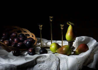 Baskets of plums and pears on a white tablecloth