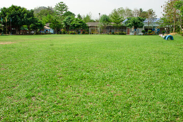 Well maintained green lawn landscape That is within the school grounds behind him.