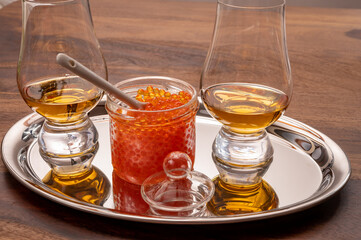 Pairing of single malt scotch or japanese whisky and salted red trout fish caviar in glass jar