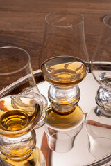 Tasting glasses of single malt scotch whisky served on steel mirror tray with reflection