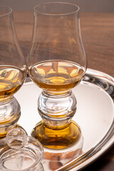 Tasting glasses of single malt scotch whisky served on steel mirror tray with reflection