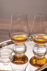 Tasting glasses of single malt scotch whisky served on steel mirror tray with reflection