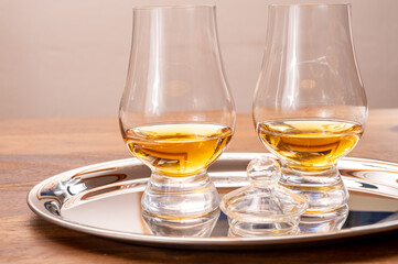 Tasting glasses of single malt scotch whisky served on steel mirror tray with reflection