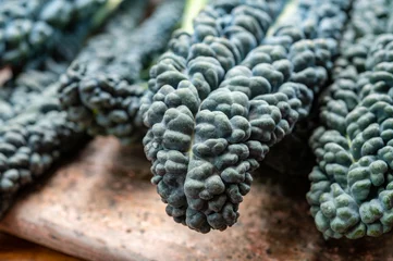 Fotobehang Cooking with black flat leaves of cavolo nero tuscan cabbage © barmalini