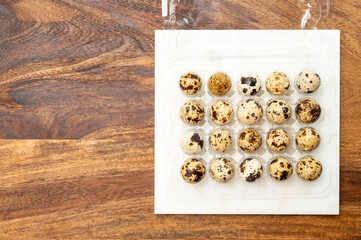 Fresh small spotted partridge eggs in tranparent plastic container