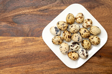Fresh small spotted partridge eggs on white board