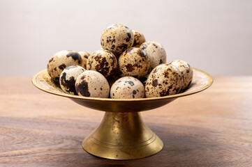 Fresh small spotted partridge eggs on bronze plate