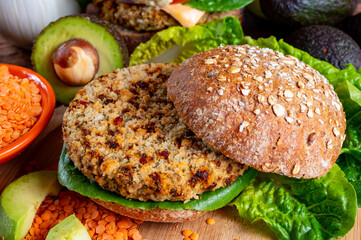 Tasty vegetarian healthy food, homemade burgers made from orange lentils legumes with green lettuce and fresh ripe avocado