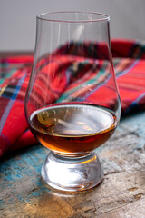 One dram of scotch whisky with red scottish tartan on background