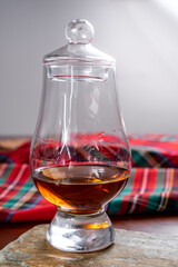 One dram of scotch whisky with red scottish tartan on background