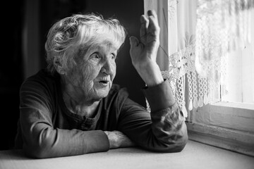 An old woman talking gesticulating at the table. Black and white photo.