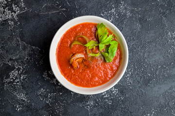 Soup cream of tomato with shrimps and greens on dark concrete table top view
