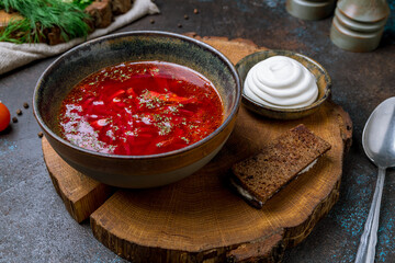 Borscht with sour cream on beautiful board on dark concrete table