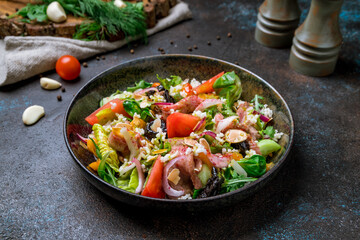 Salad with roast beef and vegetables on dark concrete table