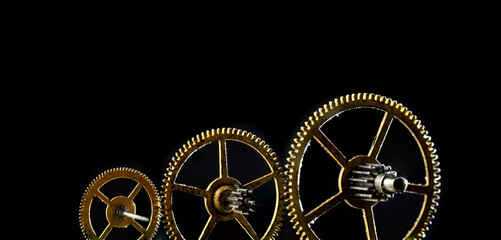 Obraz premium Three gears of different sizes on a black background. Panoramic photo.
