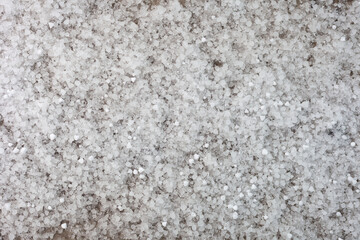 Small hailstones a solid layer lie on the yellow layer of sand