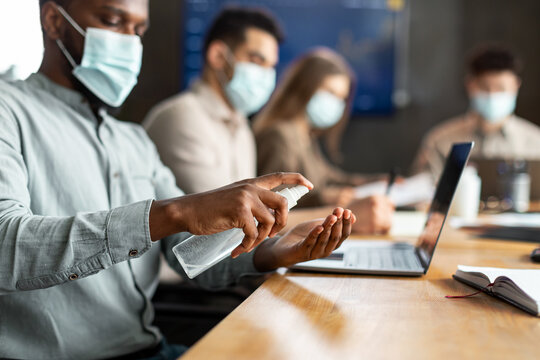 International workers wearing medical masks using sanitizer