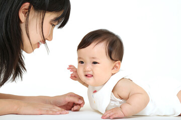 白背景でハイハイする新生児と向き合うお母さんのクローズアップ。赤ちゃん,幸福,育児イメージ