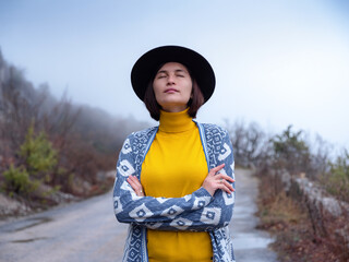 Stylish hipster woman in a hat walking down a mountain road