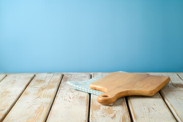Empty wooden table with tablecloth and cutting board over blue wall  background.  Kitchen mock up...