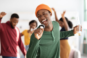 Positive black guy with bottle of beer singing karaoke