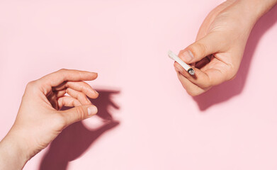 Passing cannabis cigarette from hand to hand. Cannabis smoking concept. pastel colour photo of...