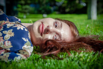 red haired woman in the park, pretty woman in the grass, pretty woman lying on the grass
