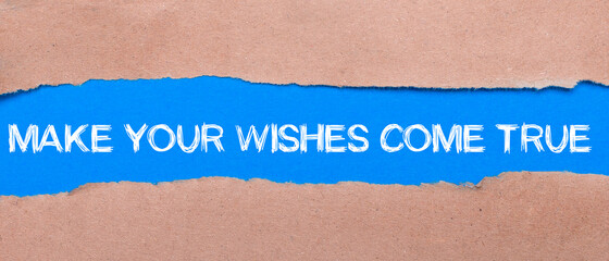 A strip of blue paper with the inscription MAKE YOUR WISHES COME TRUE between the brown paper. View from above