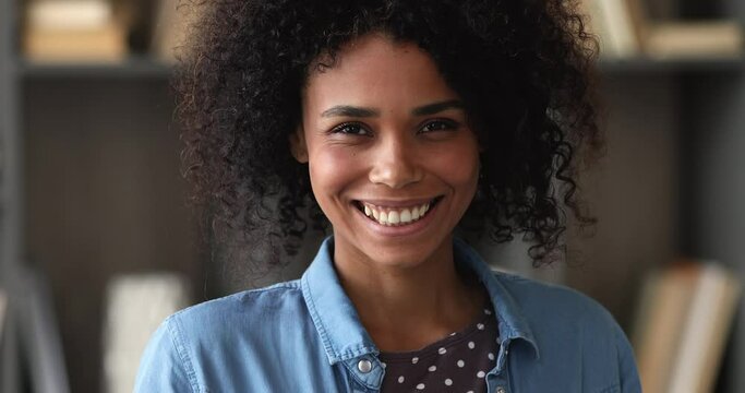 Close up portrait beautiful African woman looking at camera, female having natural black afro hair with wide beaming toothy smile pose indoor, bleaching whitening procedure services clinic ad concept