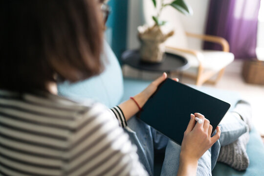 Young woman using tablet, spending leisure time chatting in social network, freelancer working online. Working from home in quarantine lockdown. Education online.
