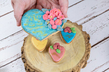 Hand holding a shortbread cookie, decorated with rolling fondant and royal icing.