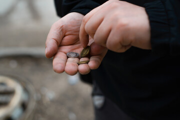 Man counts coins in his palm, outside. Close-up, selective focus. Concept of poverty, misery, bankruptcy, homeless.