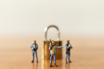 Business and Security Concept. Group of soldier or Police miniature figure people with machine gun standing with golden master key lock on wooden table.