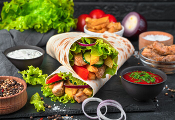 Turkish doner kebab with grilled meat and vegetables on a black background. Juicy shawarma, fast...