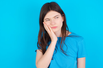 young beautiful Caucasian woman wearing blue T-shirt over blue wall with toothache