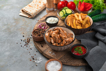 Grilled meat, French fries and vegetables on a gray background