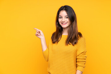 Young caucasian woman isolated on yellow background pointing finger to the side