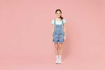 Full length young friendly smiling happy cheerful caucasian woman 20s in trendy denim clothes blue t-shirt looking camera isolated on pastel pink background studio portrait. People lifestyle concept
