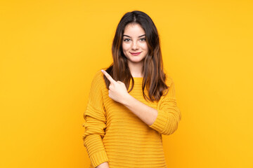 Young caucasian woman isolated on yellow background pointing to the side to present a product