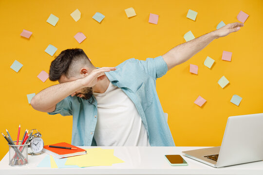 Young Employee Business Man In Shirt Sit Work At White Office Desk With Pc Laptop Doing Dab Hip Hop Dance Hands Move Gesture Youth Sign Hide Cover Face Isolated On Yellow Background Studio Portrait.