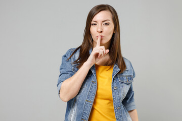 Young secret caucasian woman 20s wearing casual denim jacket yellow t-shirt saying hush be quiet...