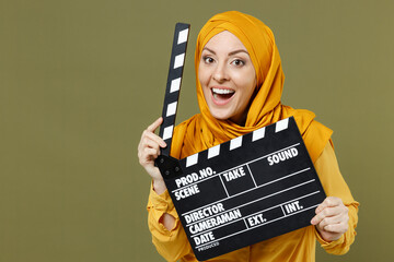 Smiling fun happy young arabian asian muslim woman in abaya hijab yellow clothes holding classic...
