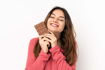 Young caucasian woman isolated on pink background taking a chocolate tablet and happy