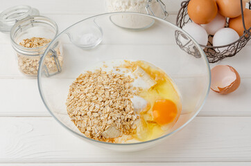 Cooking oatmeal pancakes with bananas. Eggs, buttermilk, sugar, vanilla, oatmeal in a bowl on a...