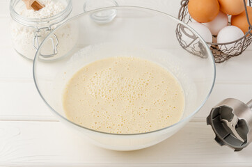 Cooking oatmeal pancakes with bananas. Eggs, buttermilk, sugar, vanilla, oatmeal in a bowl on a white wooden background. Recipe step by step.